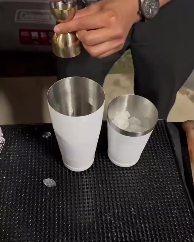 A Mix Fix bartender building a cocktail, measuring a pour into shaker tins