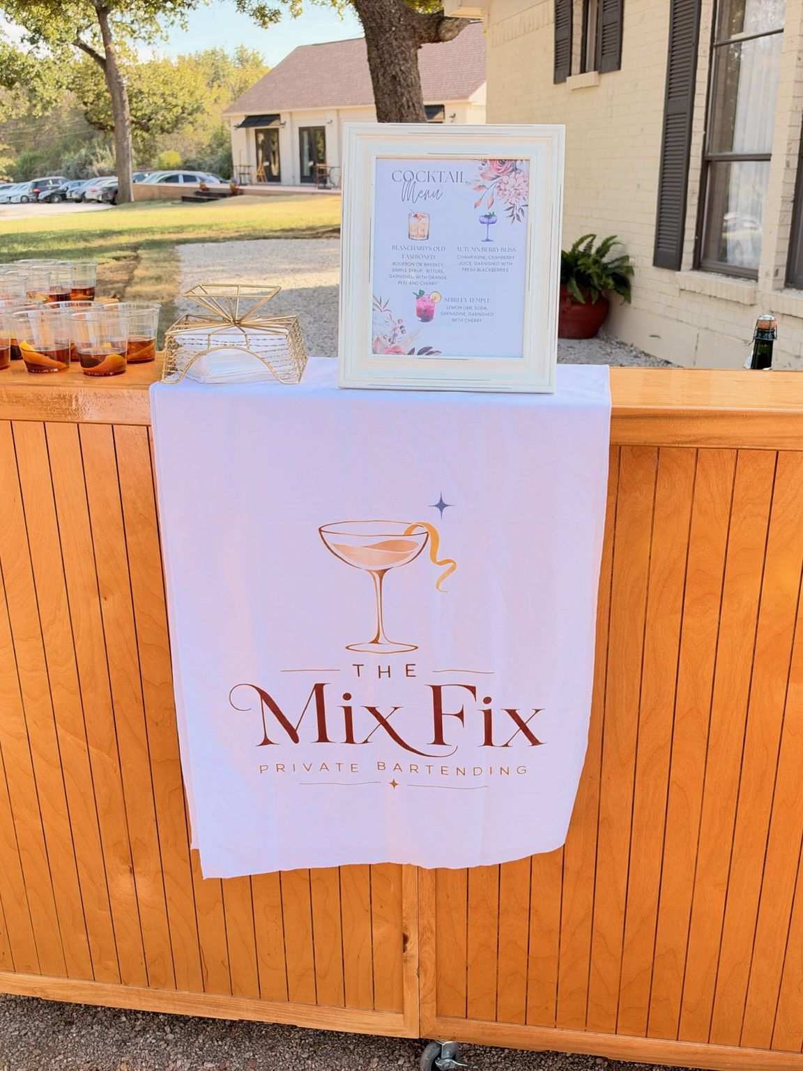 The Mix Fix wooden bar with the branded runner and framed menu, set outdoors before guests arrive