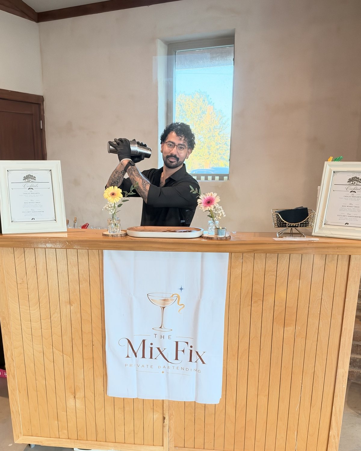 A Mix Fix bartender shaking a cocktail behind the wooden bar, menus framed on either side